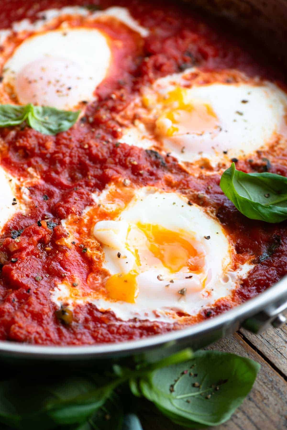 A close up of eggs in purgatory with a runny yolk in a pan.