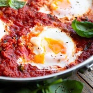 A close up of a perfectly cooked poached egg in tomato sauce with a runny yolk.