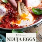A hand dunking into a runny egg yolk in a tomato sauce. The text overlay reads: Nduja Eggs in Purgatory - get the recipe.