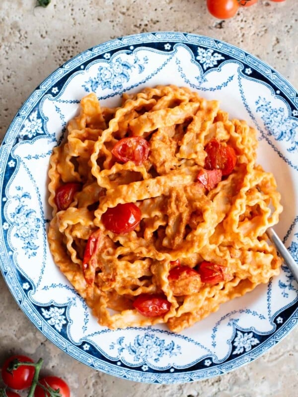 Pasta ribbons in a creamy tomato sauce in a blue and white vintage style bowl with sauteed cherry tomatoes on top.