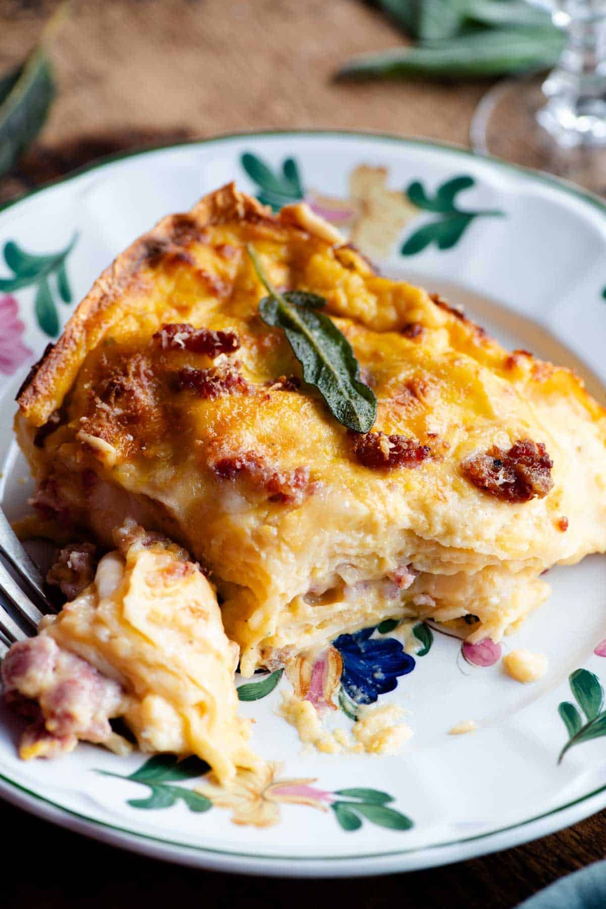 A slice of butternut squash lasagna on a floral patterned plate.