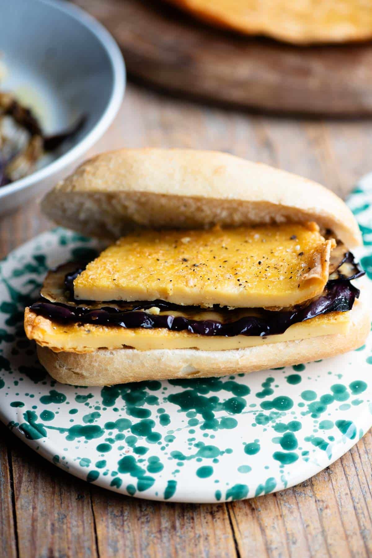 An open view of a 5x5 sandwich filled with a chickpea flatbread and eggplant.