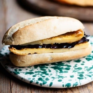 A close up of a roll filled with a chickpea flatbread and marinated eggplant.
