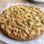 An Italian Pistachio crumb cake on a travertine surface.