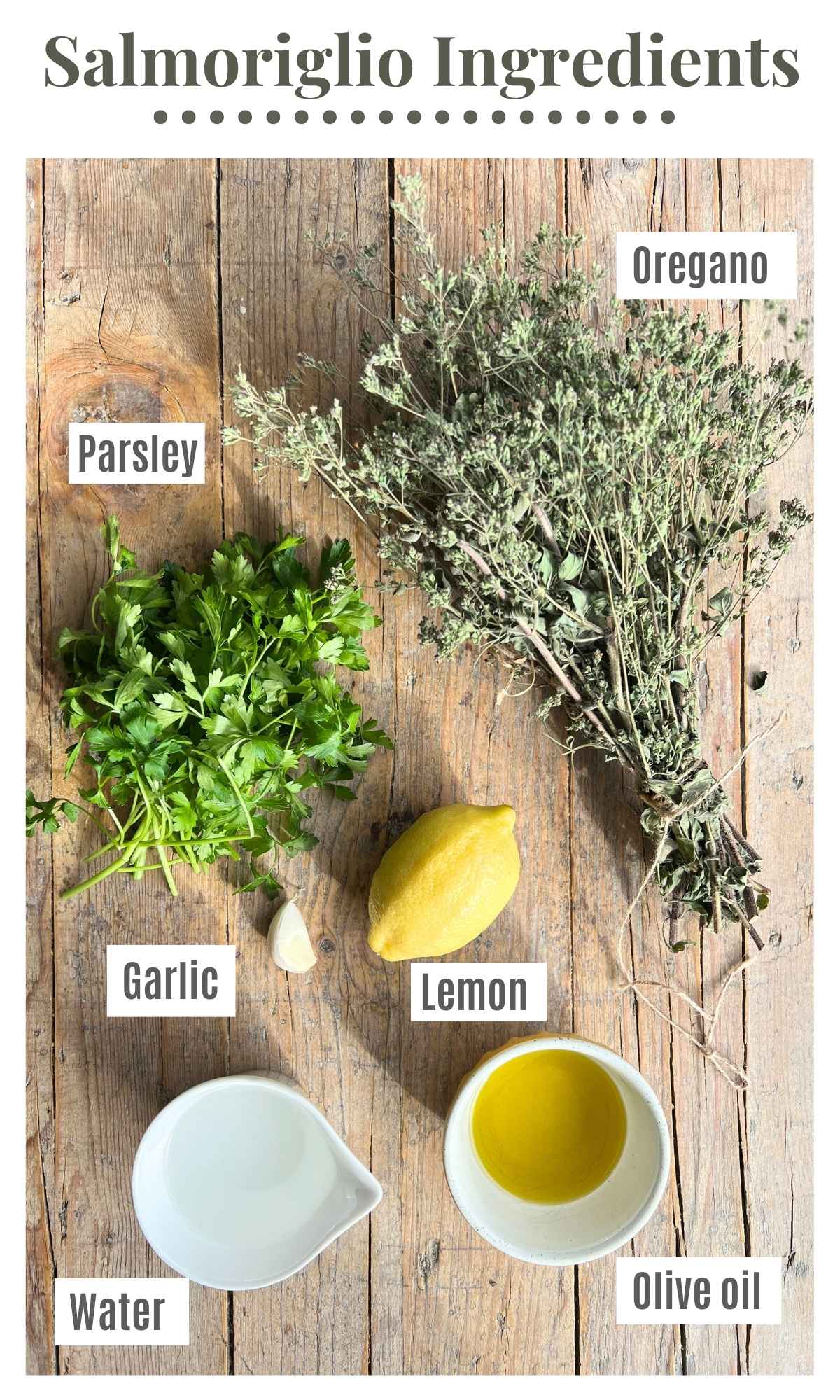 Dried oregano, parsley, olive oil, lemon, garlic, and water laying on a wooden surface.