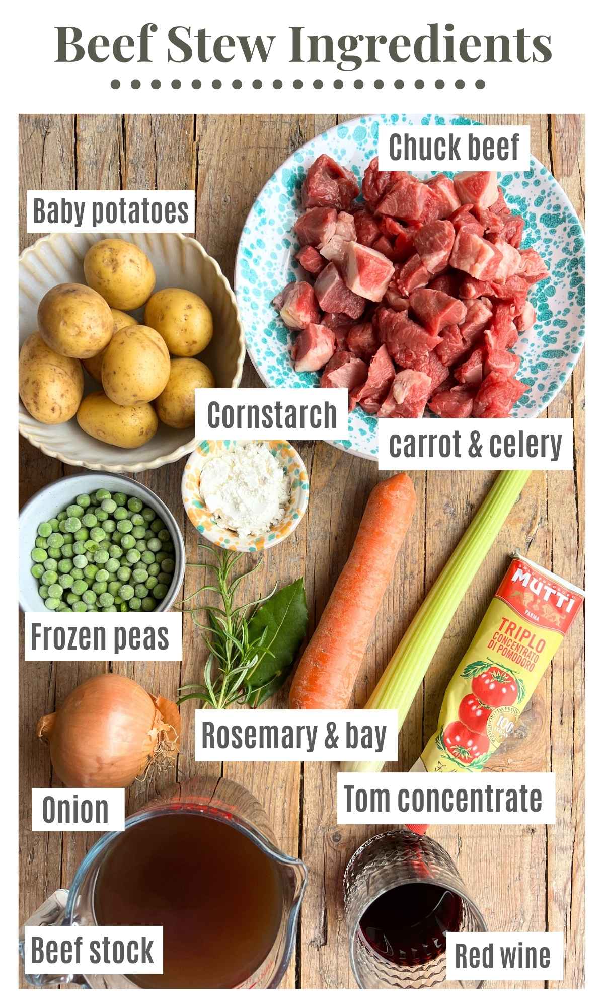 All the ingredients needed to make an Italian beef stew laying on a rustic wooden board. They text labels read: chuck beef, carrot and celery, baby potatoes, frozen peas, tom concentrate, onion, red wine, beef stock, cornstarch.