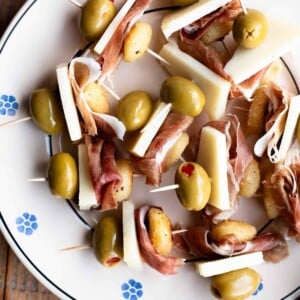 A close up of fried gnocchi on skewers with prosciutto, pecorino and olives.