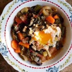 A close up cropped image of Acquacotta soup topped with a poached egg in a bowl.
