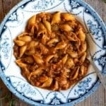 Pasta and lentils in a blue and white vintage bowl sitting on a wooden surface.