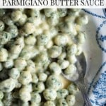 Bowl of green spinach and potato gnocchi shaped into small balls coated in a creamy cheese and butter sauce, with text overlay reading “Spinach Gnocchi Parmigiano Butter Sauce.”