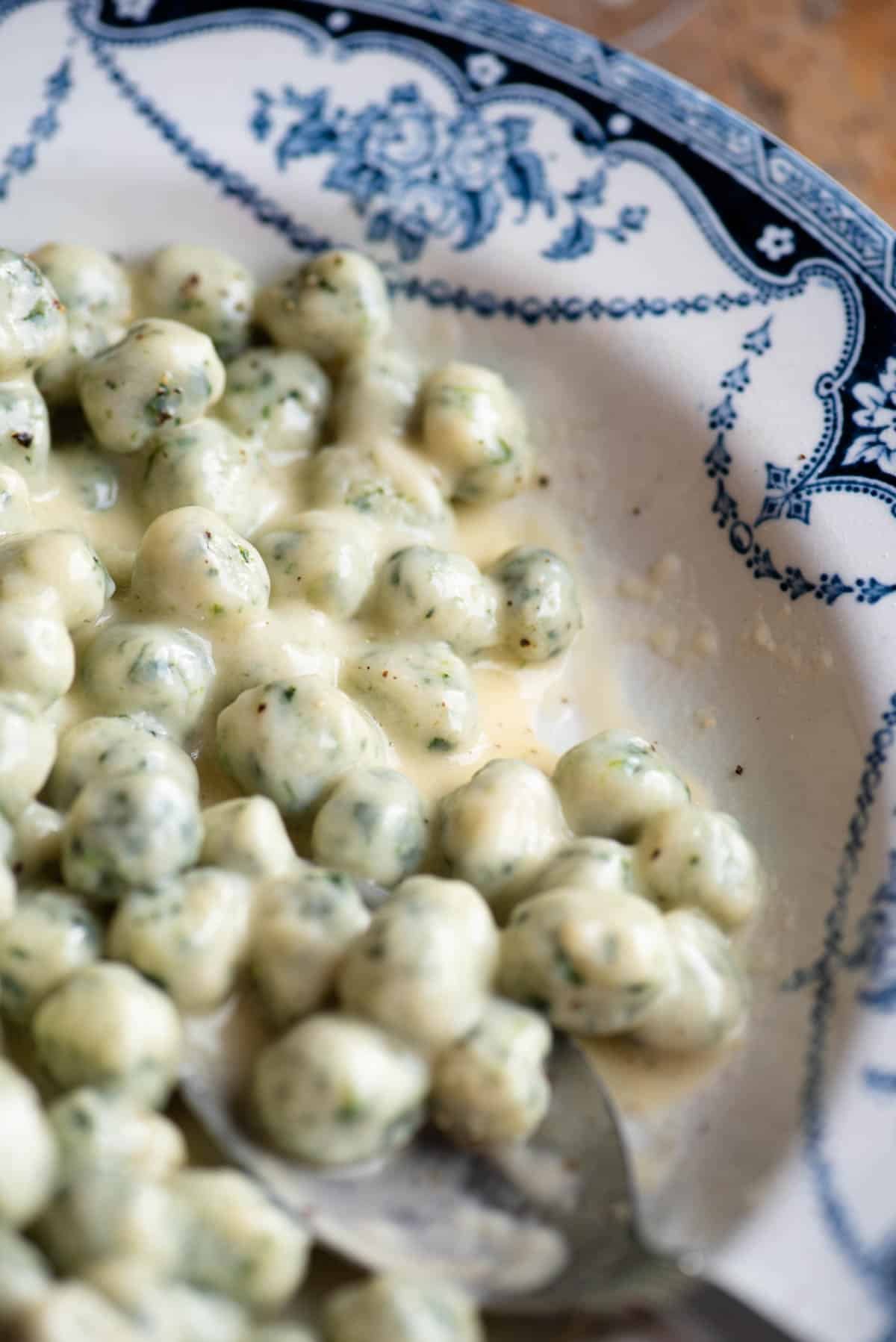 A close up of mini spinach and potato gnocchi with a creamy butter and parmigiano sauce.
