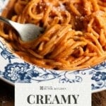 A pinterest graphic showing a close up of spaghetti in a creamy red pepper sauce around a fork in a bowl.