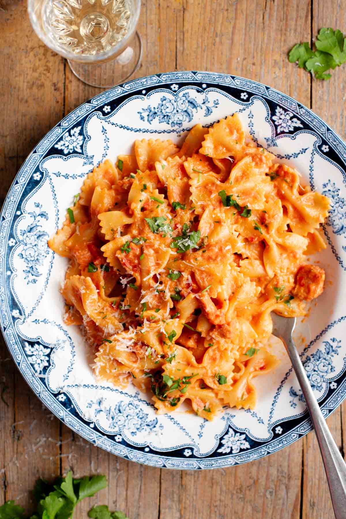 An overhead shot of farfalle pasta with a creamy tomato, garlic and chilli sauce in a blue and white bowl.