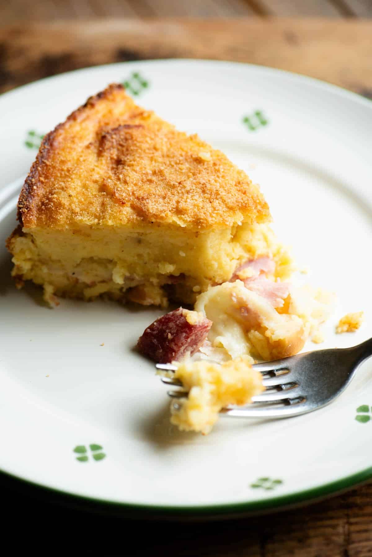 A close up of a slice of Neapolitan potato cake (gatto di patate) on a plate with a fork.