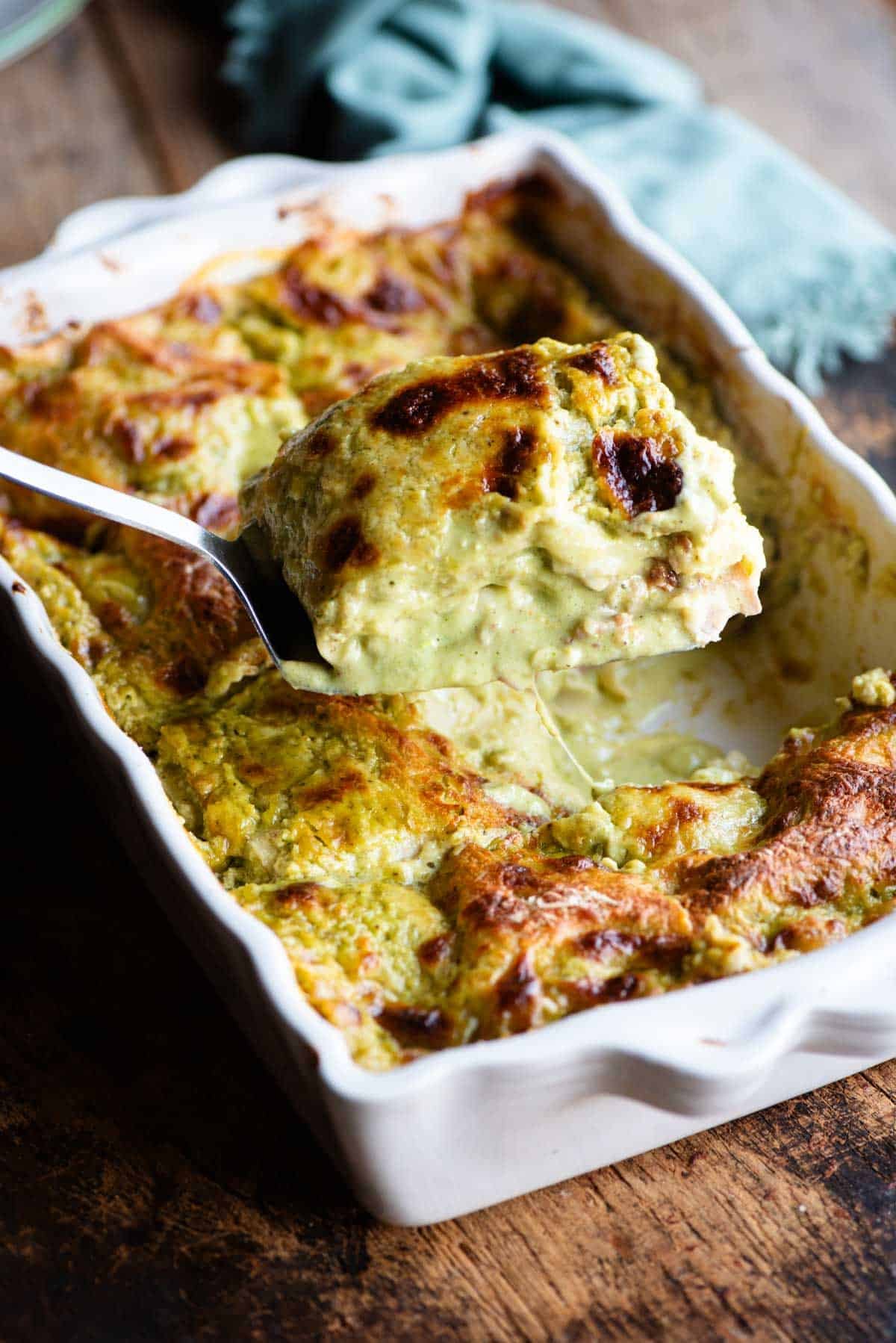 A spatula picking a slice of pistachio lasagna from a baking dish.