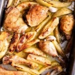 A close up cropped image of roasted chicken and potatoes in a baking tray.