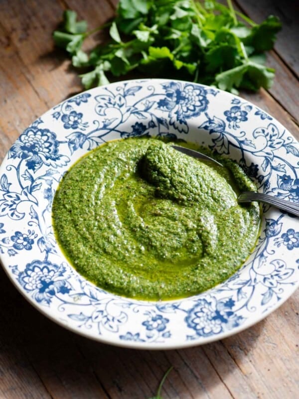 Tuscan salsa verde in a blue and white floral bowl with parsley at the side.
