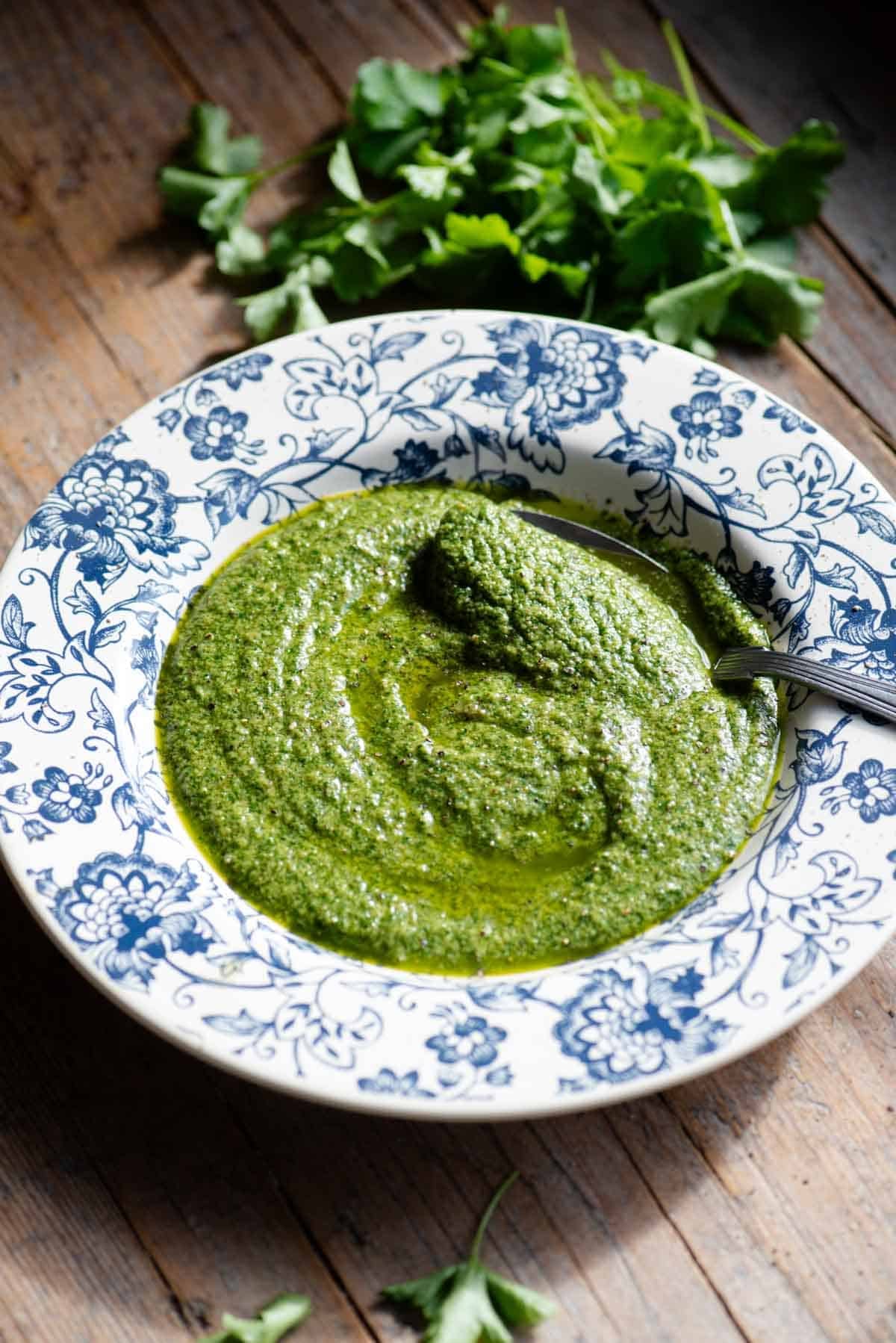 Tuscan salsa verde in a blue and white floral bowl with parsley at the side.