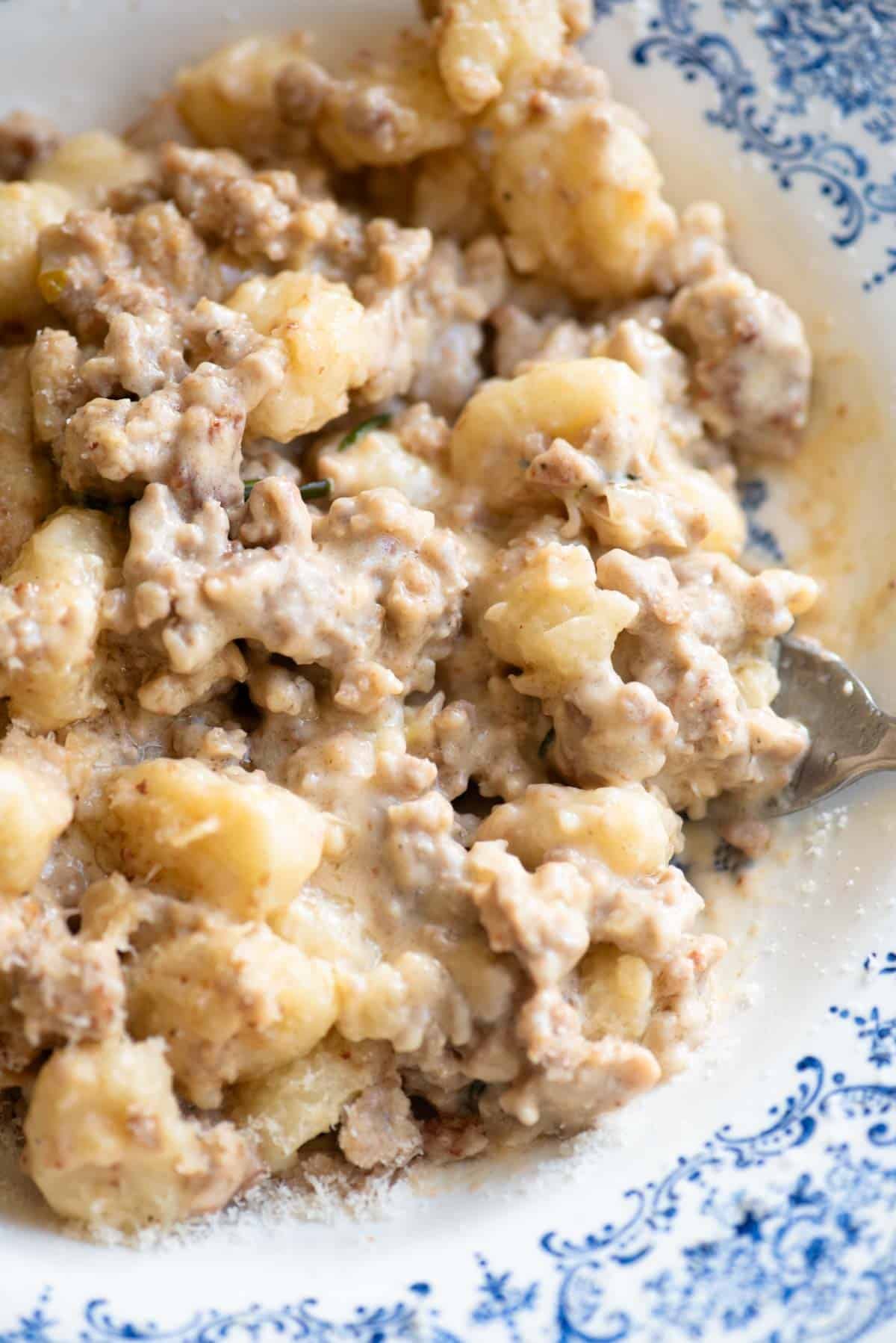A close up of gnocchi with a creamy white sausage sauce.