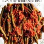 A close up of green beans on a white plate with olives and capes. The text overlay reads; Tomato Green Beans - Easy and Delicious Side Dish.