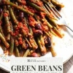 A pinterest graphic showing green beans in tomato sauce with olives and capers on a white plate.