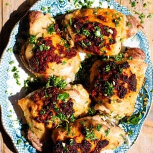 Nduja baked chicken on a blue and white serving plate topped with gremolata.