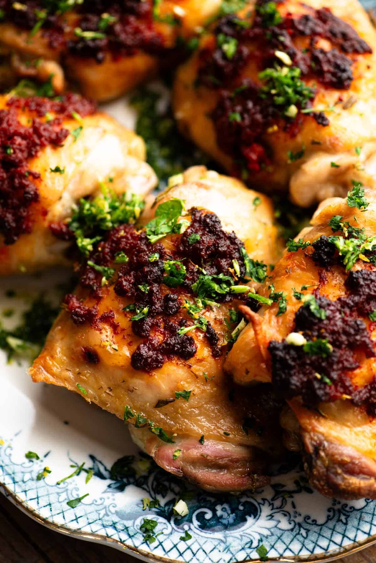 A close up of Nduja baked chicken thighs topped with gremolata.