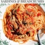 An overhead shot of a bowl of tomato pasta with sardines, capers and breadcrumbs. The text overlay reads Tomato Pasta Sardines and Breadcrumbs.
