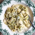 Orecchiette with broccoli, garlic and chilli in a white and green floral bowl sitting on a wooden surface.