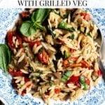 An overhead shot of an orzo pasta salad in a blue bowl. The text overlay reads; Orzo pasta Salad with Grilled veg.