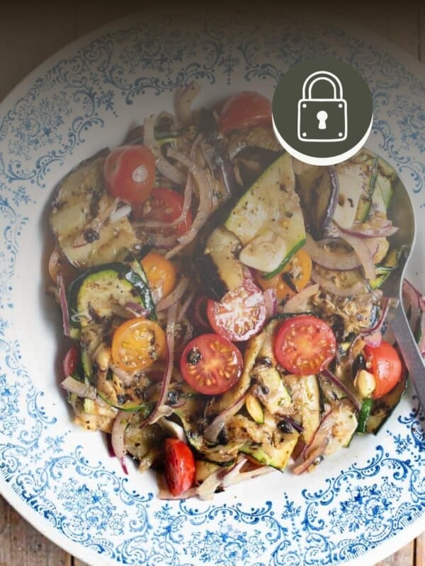Marinated summer vegetables in a blue bowl with a padlock in the top right to signify a member only recipe.