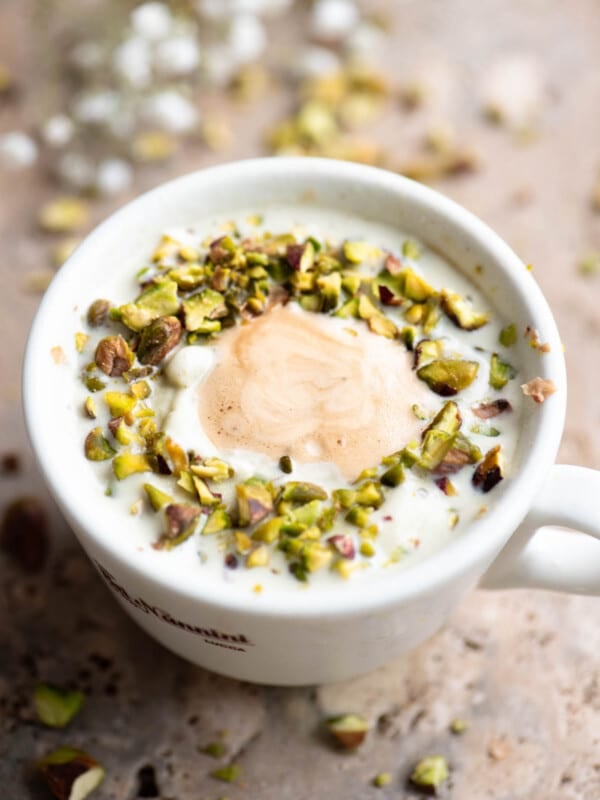 A pistachio affogato topped with chopped pistachios on a travertine surface.