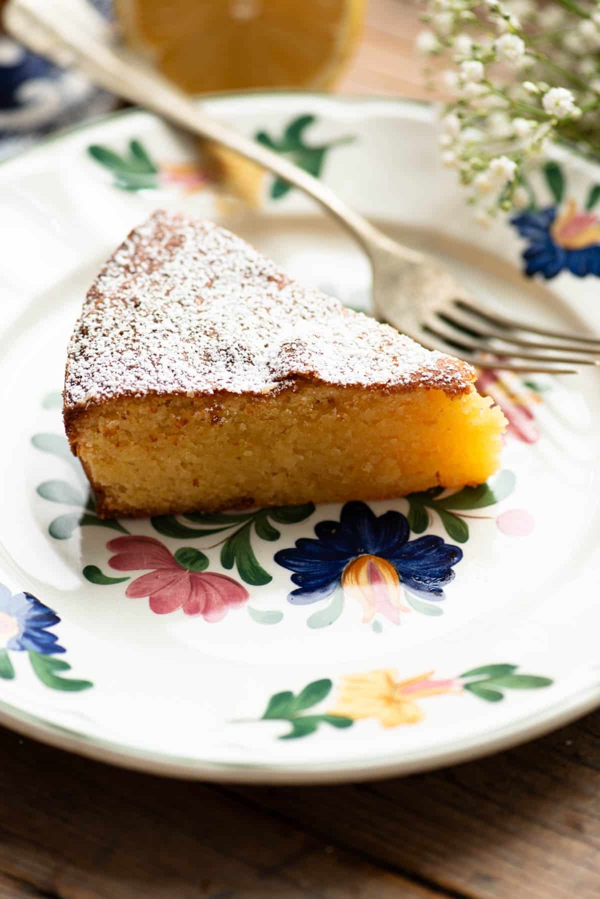 A close up of a slice of white chocolate caprese cake on an Italian floral plate.