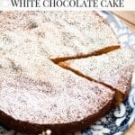 A pinterest graphic showing a white Italian cake dusted in powdered sugar. The text overlay reads Torta Caprese Bianca - White Chocolate Cake