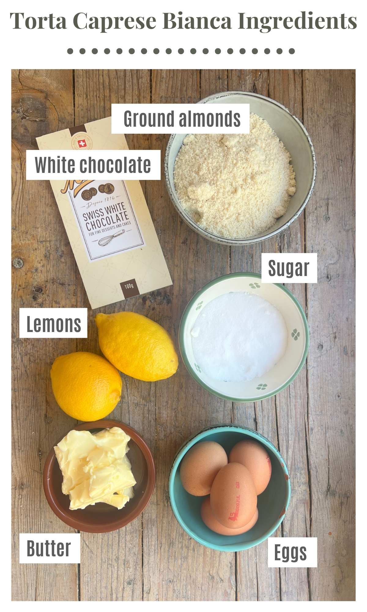An overhead shot of all the ingredients needed to make a torta caprese bianca laying out on a rustic wooden surface.