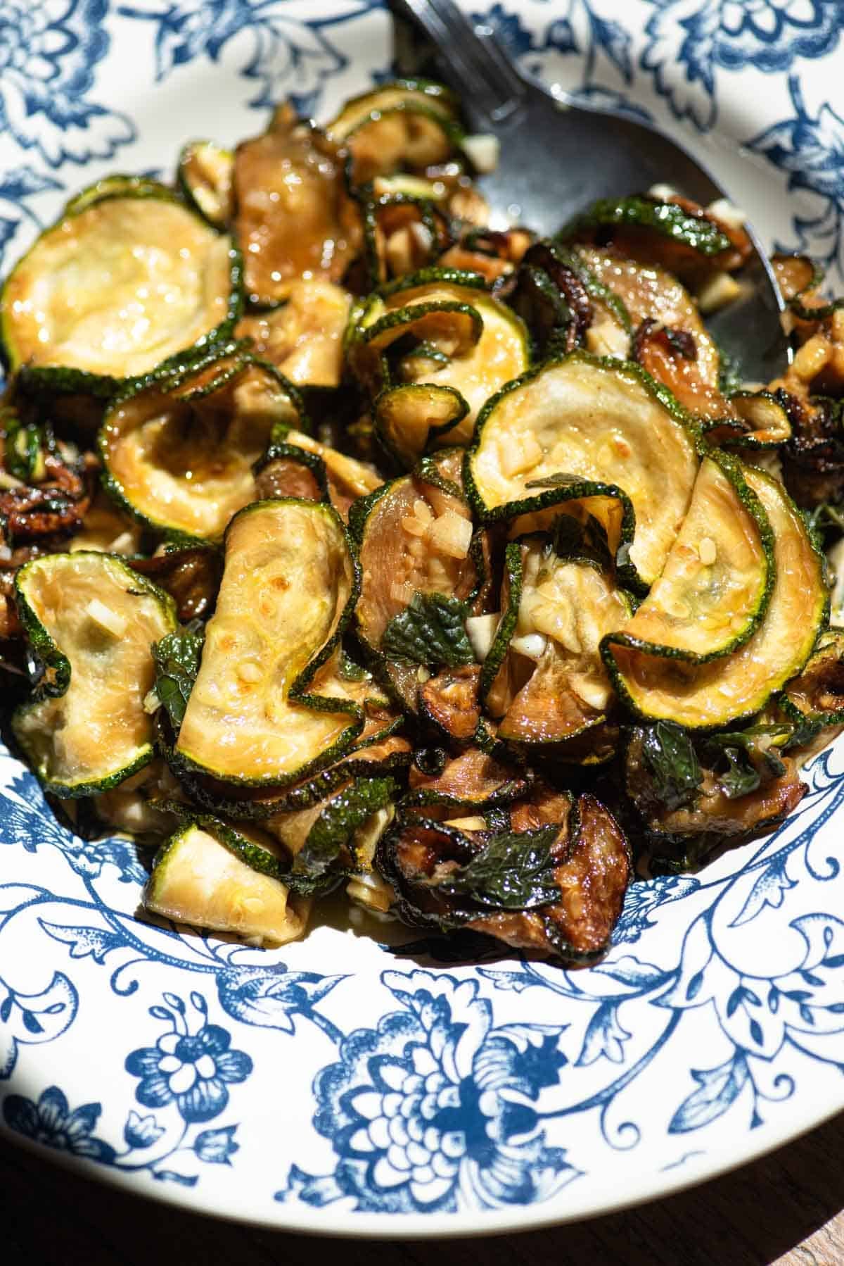A close up of fried marinated zucchini in a blue bowl.