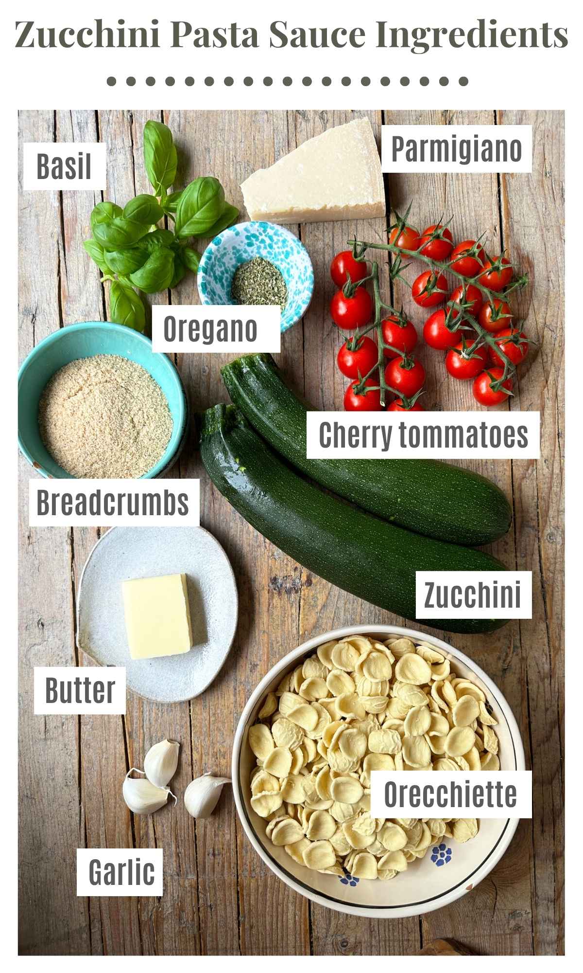 An overhead shot of the ingredients needed to make a zucchini butter pasta. Basil, parmigiano, cherry tomatoes, breadcrumbs, zucchini, orecchiette, garlic, butter and oregano.