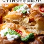 A close up of a roasted tomato focaccia showing the airy texture inside and topped with pesto and burrata.