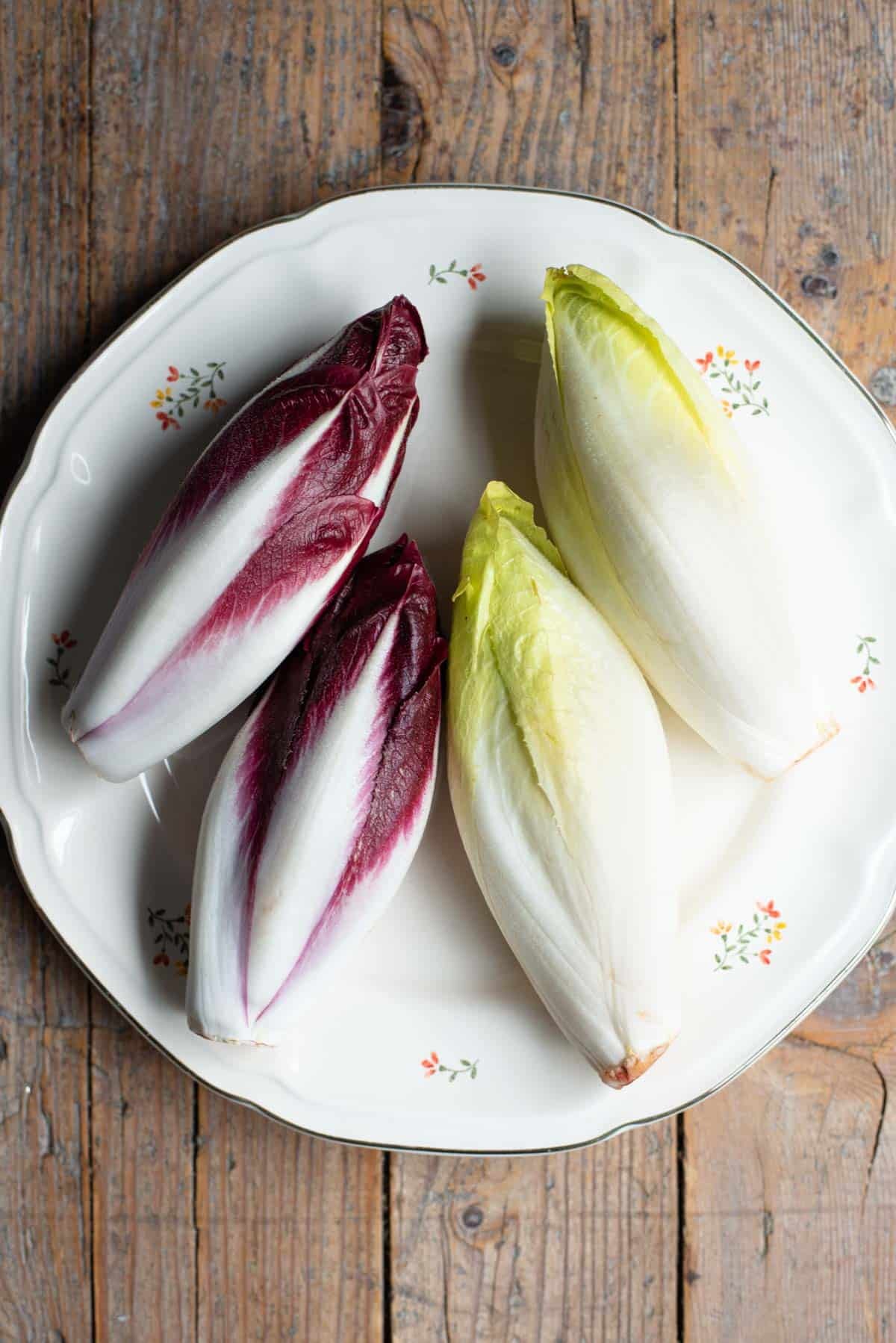 An overhead shot of red and white chicory on a plate with a rustic wooden background.