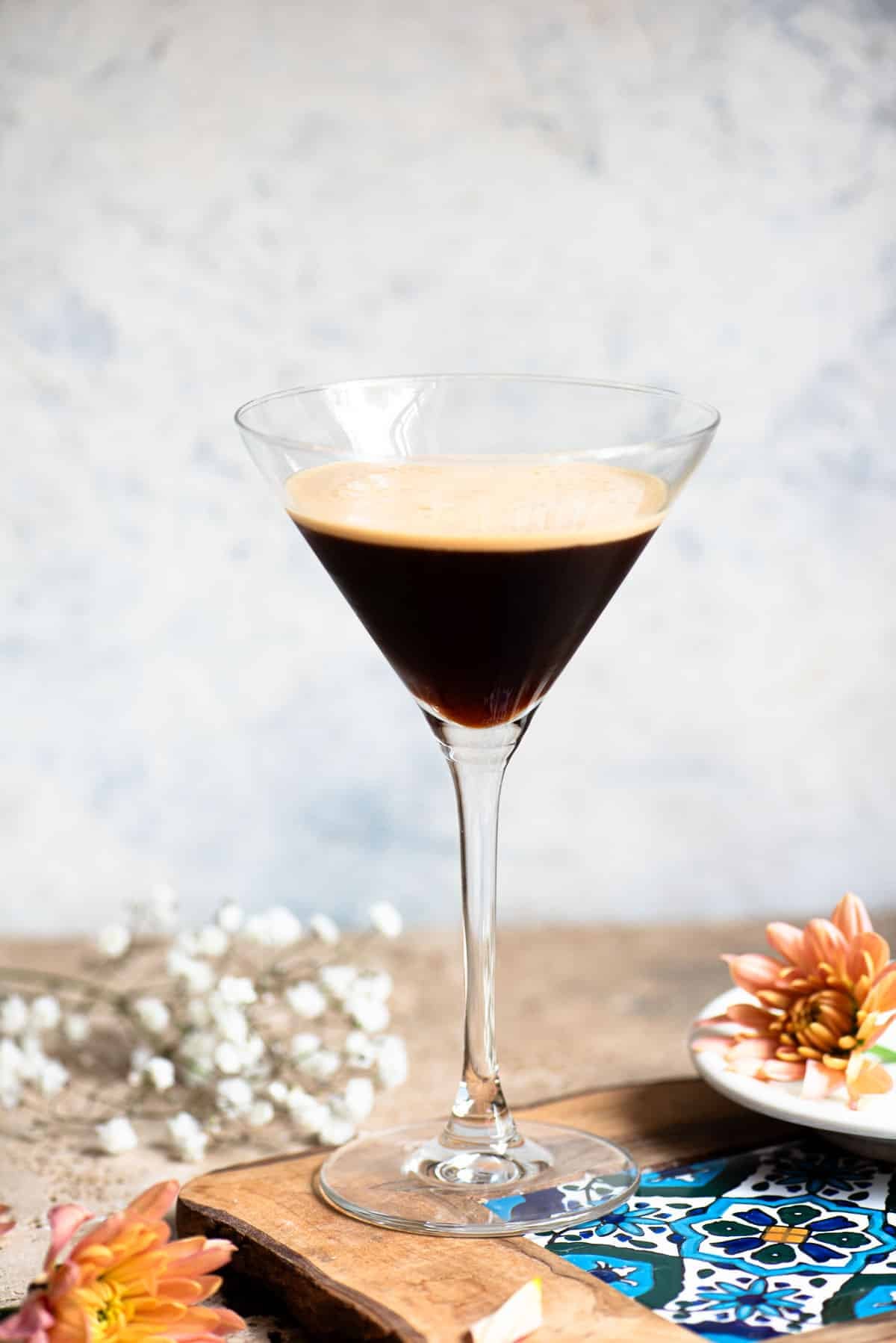 A martini glass filled with an Italian iced coffee sitting on a wooden table with flowers around.