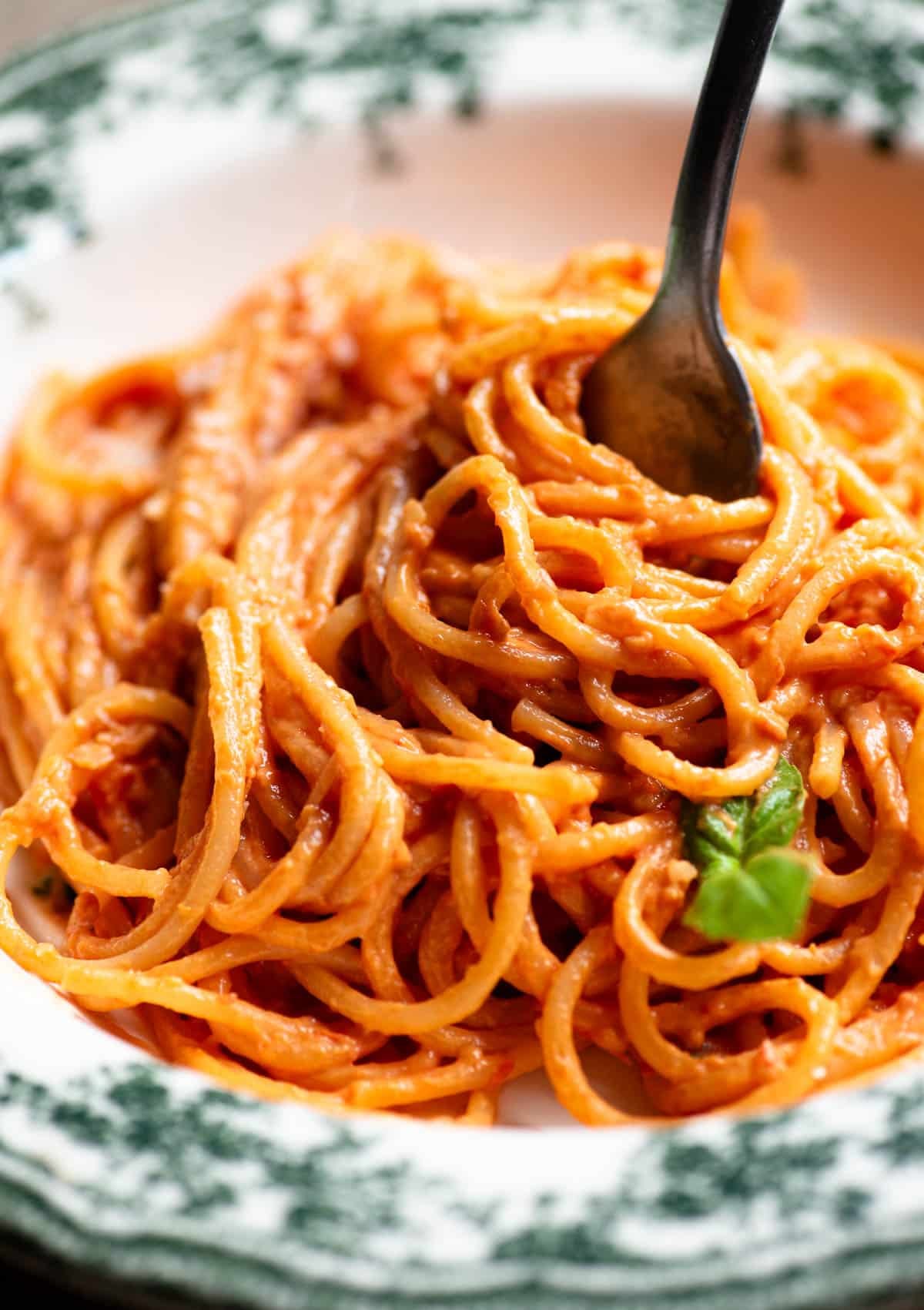 A close up of tomato and ricotta spaghetti in a bowl and twisted round a fork.