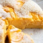 A close up of an Italian sponge cake with slices removed to see the yellow pastry cream inside.
