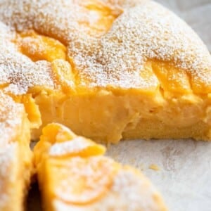 A close up of an Italian sponge cake with slices removed to see the yellow pastry cream inside.