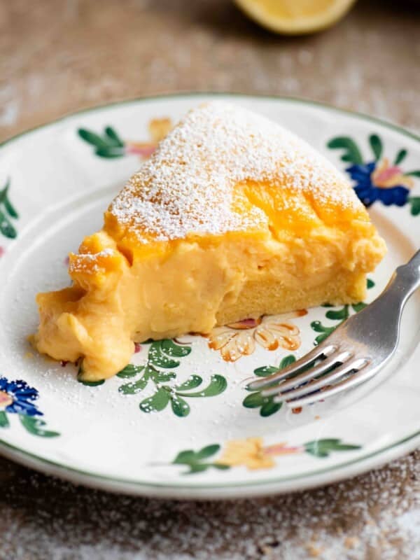 A close up of a slice of torta nua filled with pastry cream on a floral plate with a fork.
