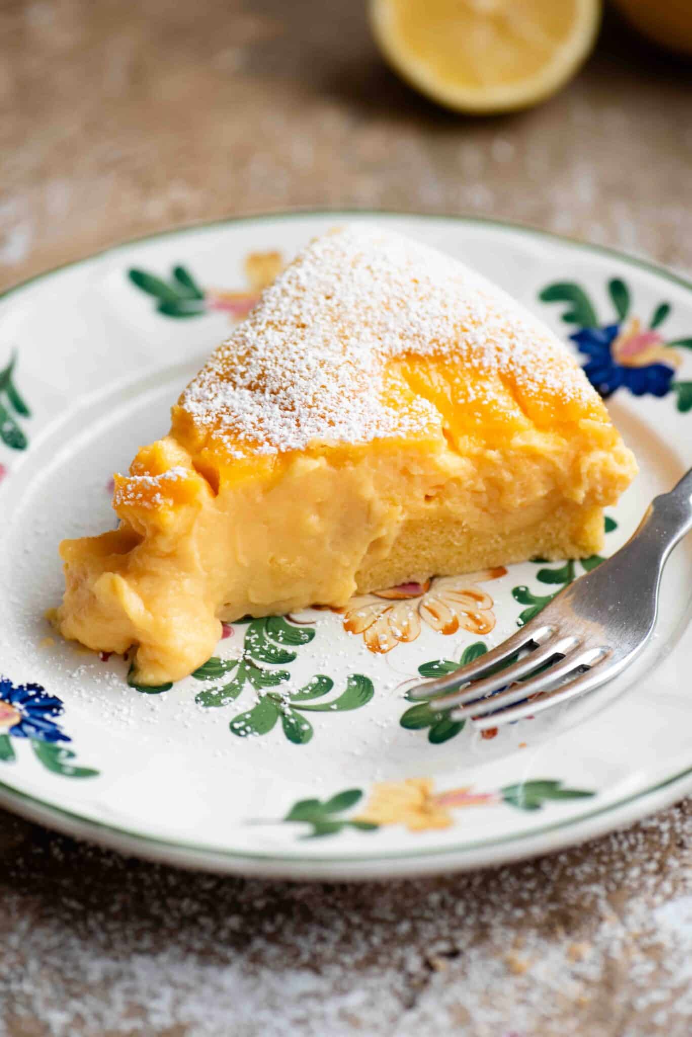 A close up of a slice of torta nua filled with pastry cream on a floral plate with a fork.