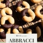 A pinterest pin of Italian abbracci cookies on a wire rack. The text overlay reads, abbracci Italian cookies - get the recipe.