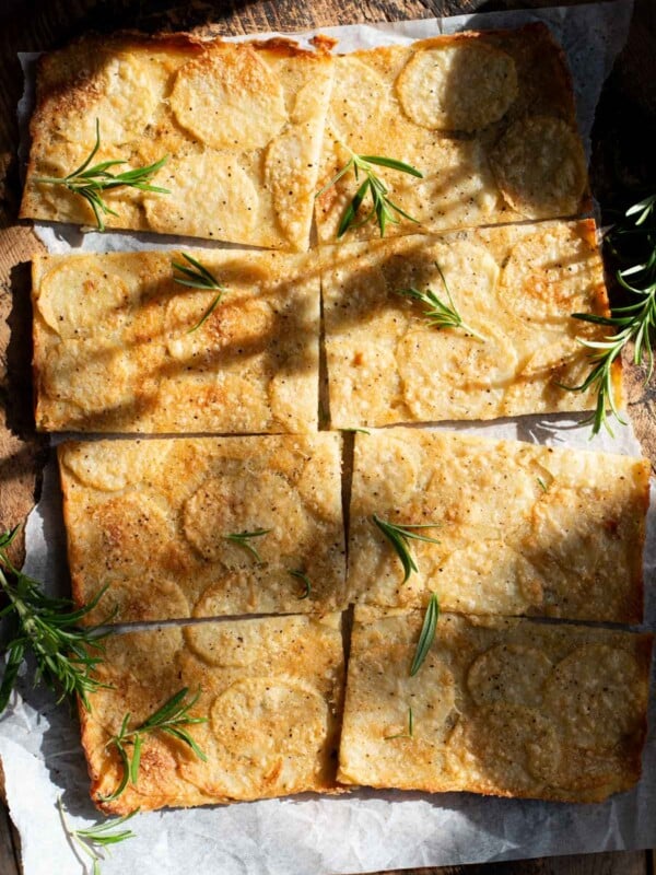An overhead shot of an Italian potato flatbread cut into 8 slices topped with rosemary.